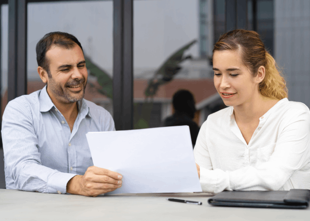 Business clients discuss contract pages with a translator in Pittsburgh, arranging Spanish Translation Services for company.